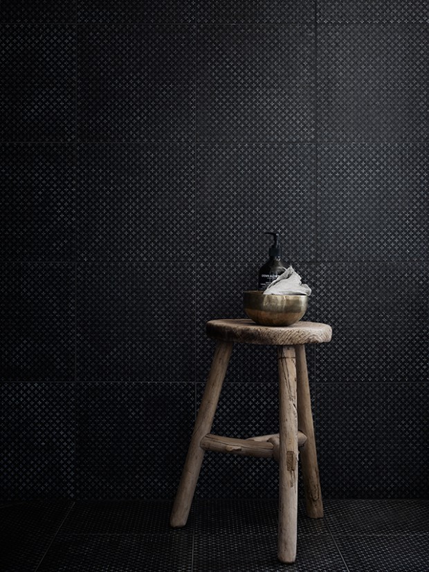 bathroom-with-black-textured-tiles.-raw-wooden-stool.